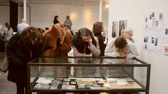 Foto: vier Frauen betrachten in der Ausstellung Fotos und Postkarten.