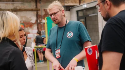 eine Person erzählt an einem Stehtisch mit mehreren Personen von ihrer Kulturorganisation