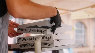 der Pizzabäcker nimmt sich einen Pizzakarton vom Stapel