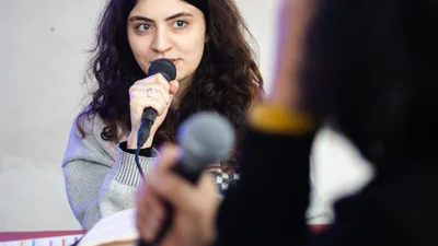 A young woman is speaking into a microphone.