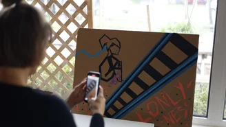Eine Person fotografiert eine Collage auf der "Loneliness" (Einsamkeit) steht