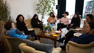 Eine Gruppe von Menschen sitzt an einem Tisch und tauscht sich aus.