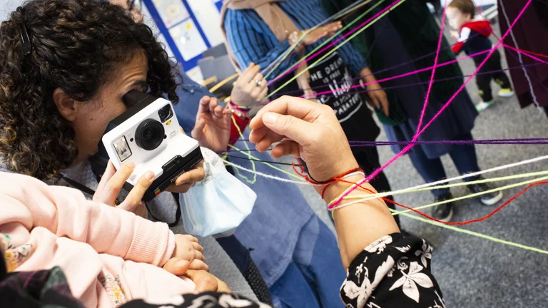 A workshop insight: A group of different people are connected by colorful threads.
