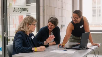 drei Personen vor einem Laptop