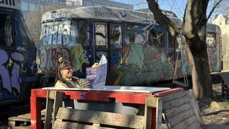 A person is sitting in an empty outdoor bathtub looking at a map.