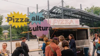 ein Pizzawagen im Freien, um den sich Menschen sammeln