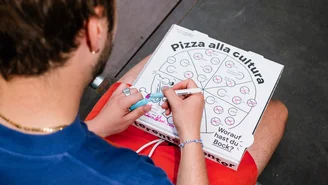 eine Person kreuzt auf einem Pizzakarton verschiedene Dinge an. Unten steht: Worauf hast du Bock?