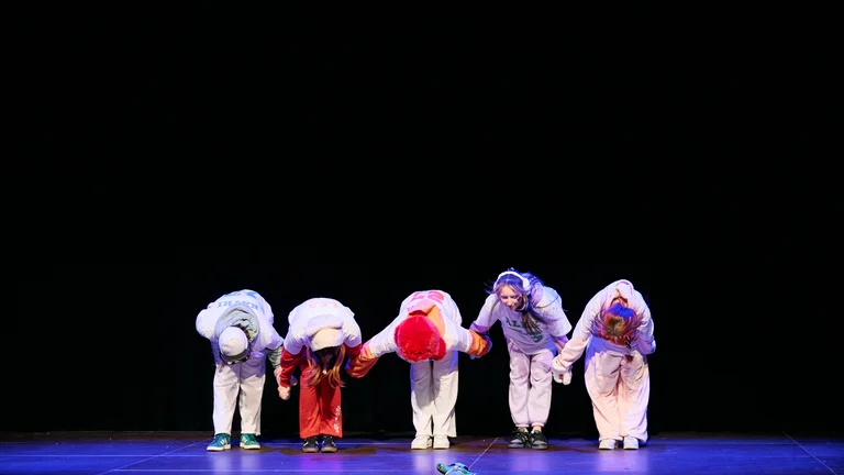 Tanzgruppe verneigt sich zusammen auf der Bühne.