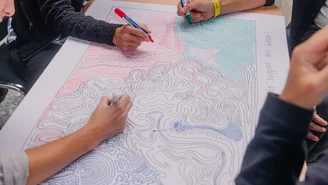 vier Personen zeichnen gleichzeitig Linien auf ein Papier, während sie über Kulturthemen sprechen