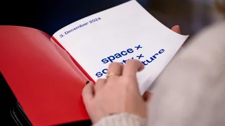 Eine Person liest ein Programmheft der Techlab Konferenz mit der Aufschrift "space, society, culture".