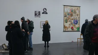 Foto: Besucher bei der Finissage, eine Frau Betrachtet Kunstwerke an der Wand.