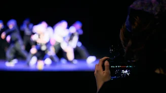 Eine Person im Publikum filmt die Tanzgruppe auf der Bühne.
