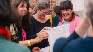 drei Personen öffnen lachend einen gestalteten Pizzakarton