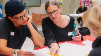 drei Personen entwickeln eine Strategie und bringen sie auf ein Plakat