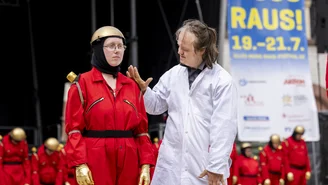 a man in a white coat taps a person dressed as a robot on the left shoulder