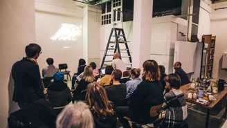 Mehrere Personen schauen ein auf eine Wand projiziertes Video