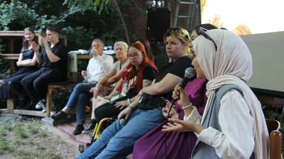 eine junge Frau mit Mikrofon in einer Gesprächsrunde