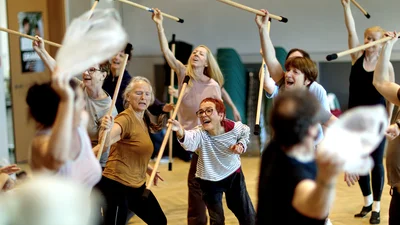 Probe von eine Stadt tanzt. Die Performer tanzen mit Holzstäben.