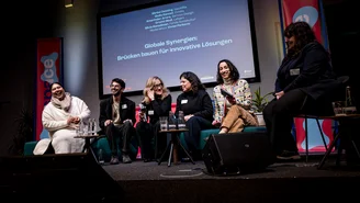 Eine Gruppe von Personen diskutiert auf der Bühne zum Thema Globale Synergien