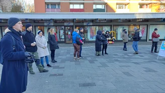 Eine Gruppe von Menschen stehen im Halbkreis vor einer Behörde