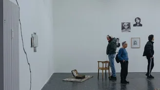 Foto: Besucher bei der Finissage, ein Mann betrachtet einen ausgestellten Koffer.
