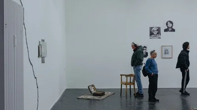 Visitors at the closing event, a man looks at a suitcase on display.