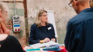 eine Frau erklärt an einem Stehtisch ihre Organisation