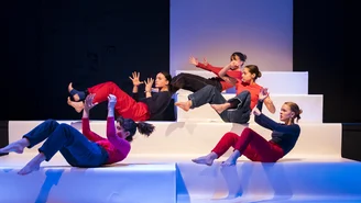 Fünf junge Frauen während einer Tanzperformance auf einer Bühne bestehend aus großen Treppenstufen.