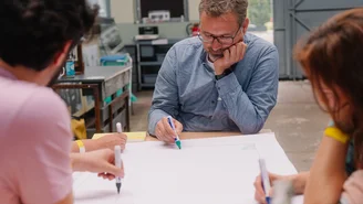 vier Personen zeichnen gleichzeitig Linien auf ein großes Blatt
