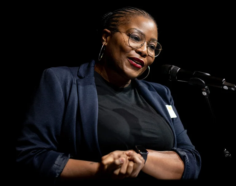 a woman stands in front of a microphone and gesticulates with her hands