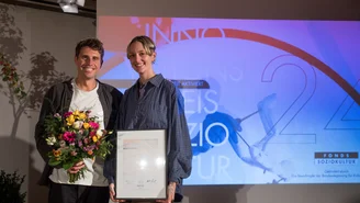 Zwei Personen aus dem Projekt mit Urkunde und Blumenstrauß