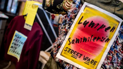 Nahaufnahme eines Wäscheständers mit Kleidung und einem Plakat, auf dem steht "Lumpensammlerin Street Ware"