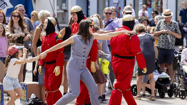 A woman taps a person dressed as a robot on the shoulder.