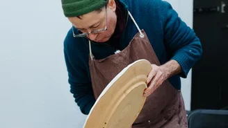 Foto: Keramikworkshop mit Enno Jäkel, ein Mann glasiert eine große Keramikplatte.