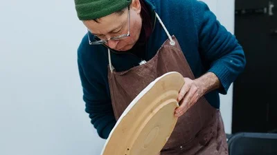 Foto: Keramikworkshop mit Enno Jäkel, ein Mann glasiert eine große Keramikplatte.